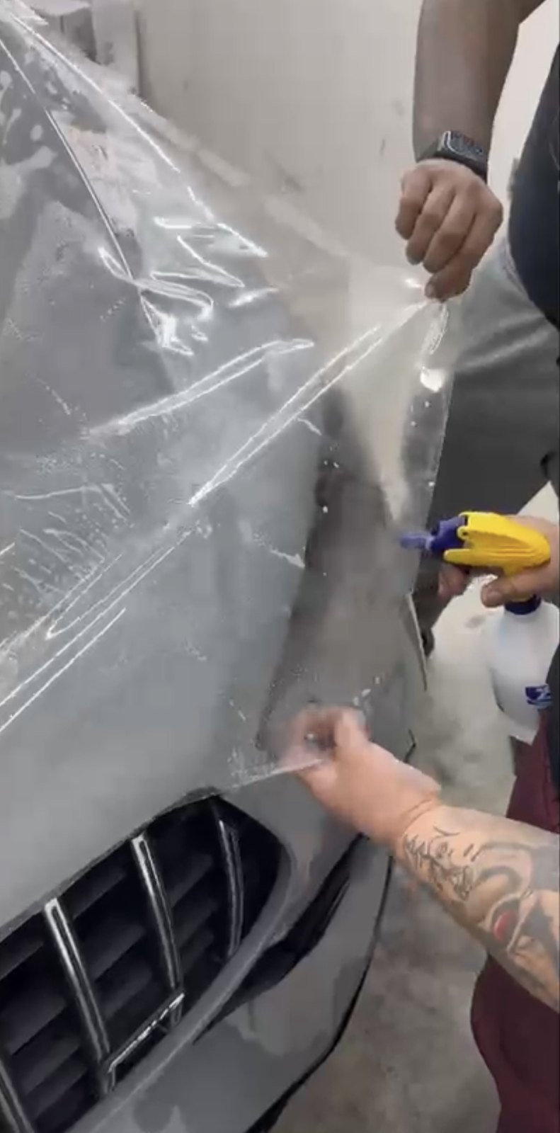 Clear paint protection film being laid onto the front fender of a car at the Pinnacle shop