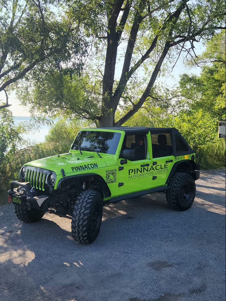 Pinnacle green Jeep Wrangler with shop graphics, parked by the water