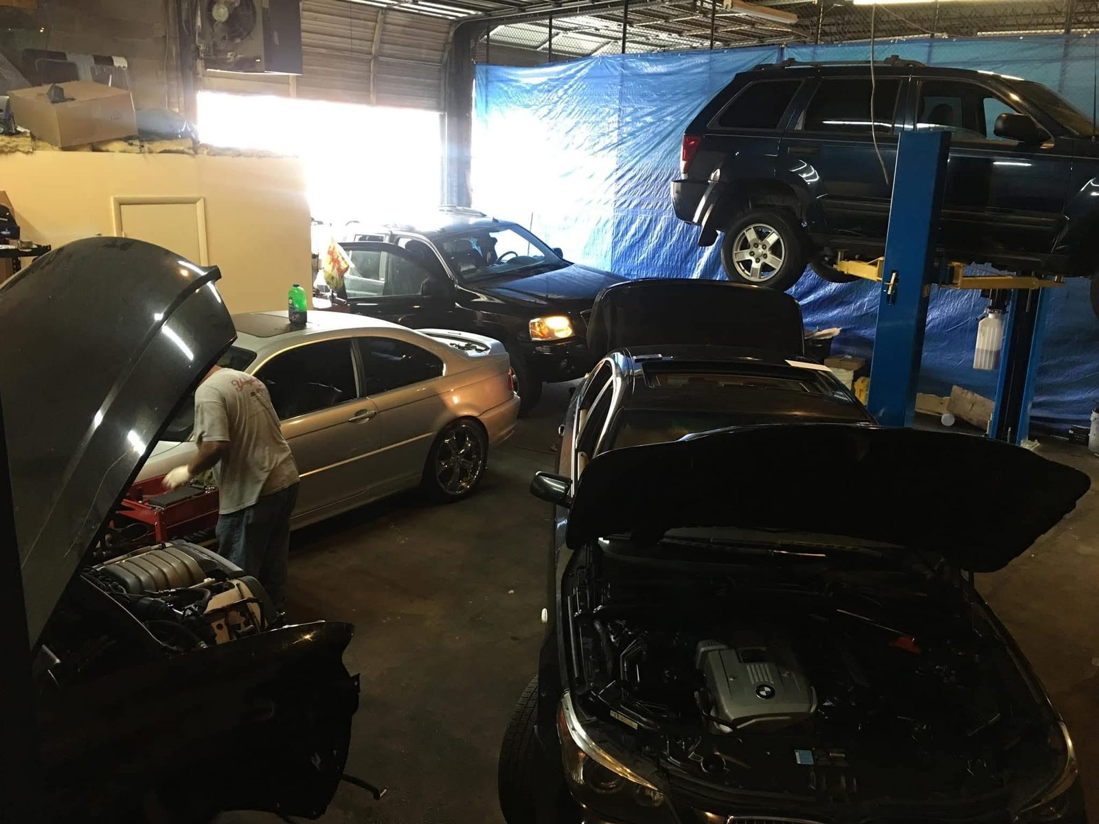 Several vehicles in for service inside Pinnacle’s Middle River shop, including cars and an SUV raised on a lift.