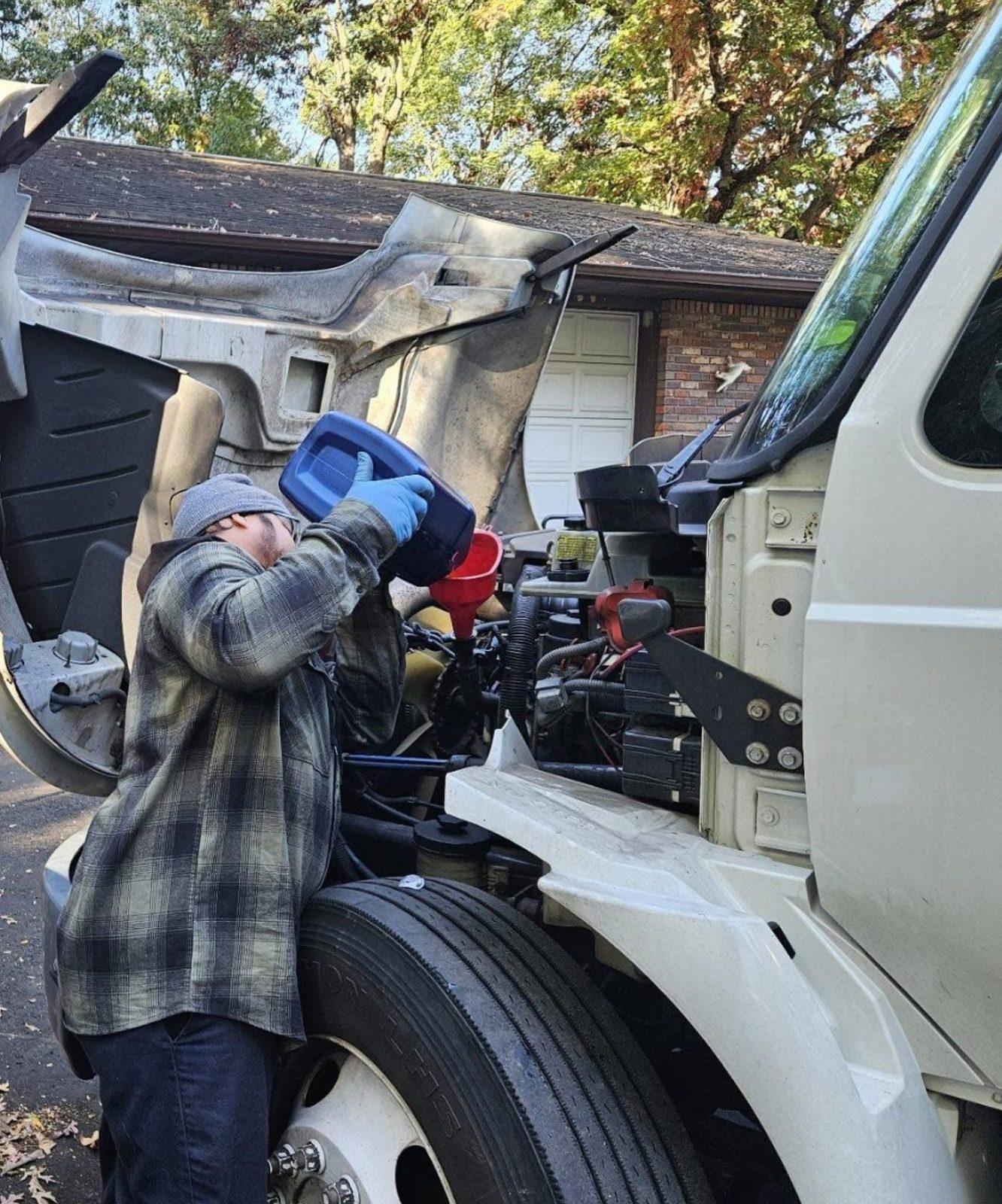 A technician adding oil to a truck engine during fluid service at Pinnacle.